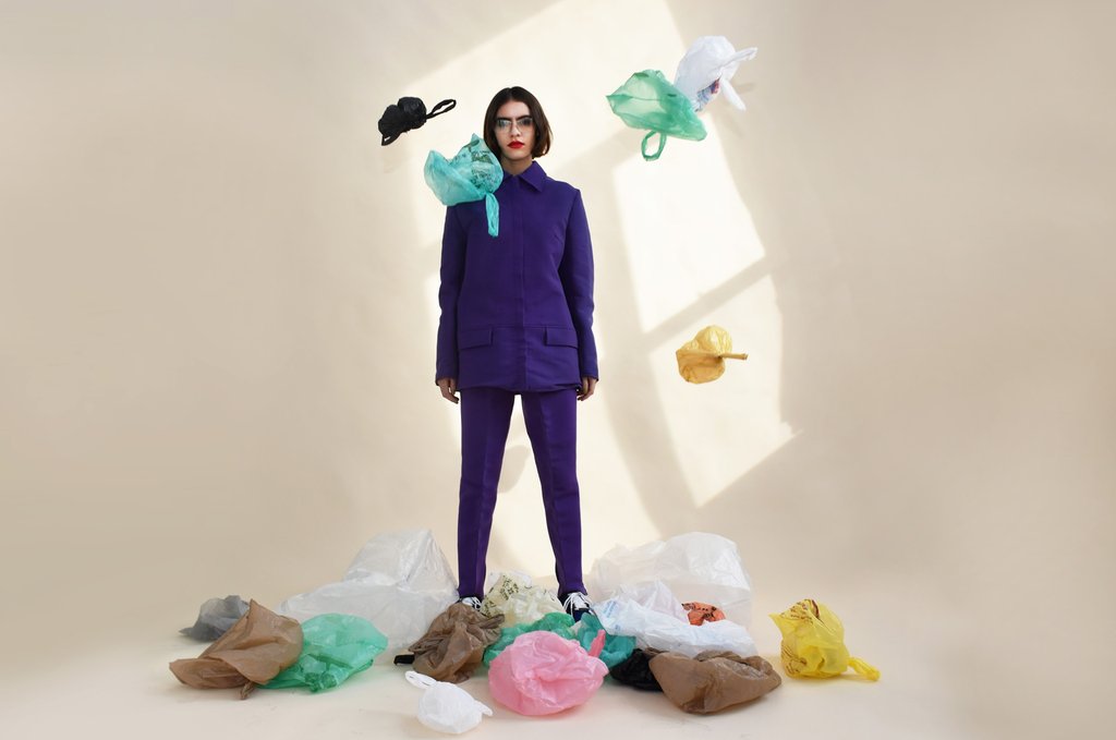 model in suit surrounded by plastic bags. 