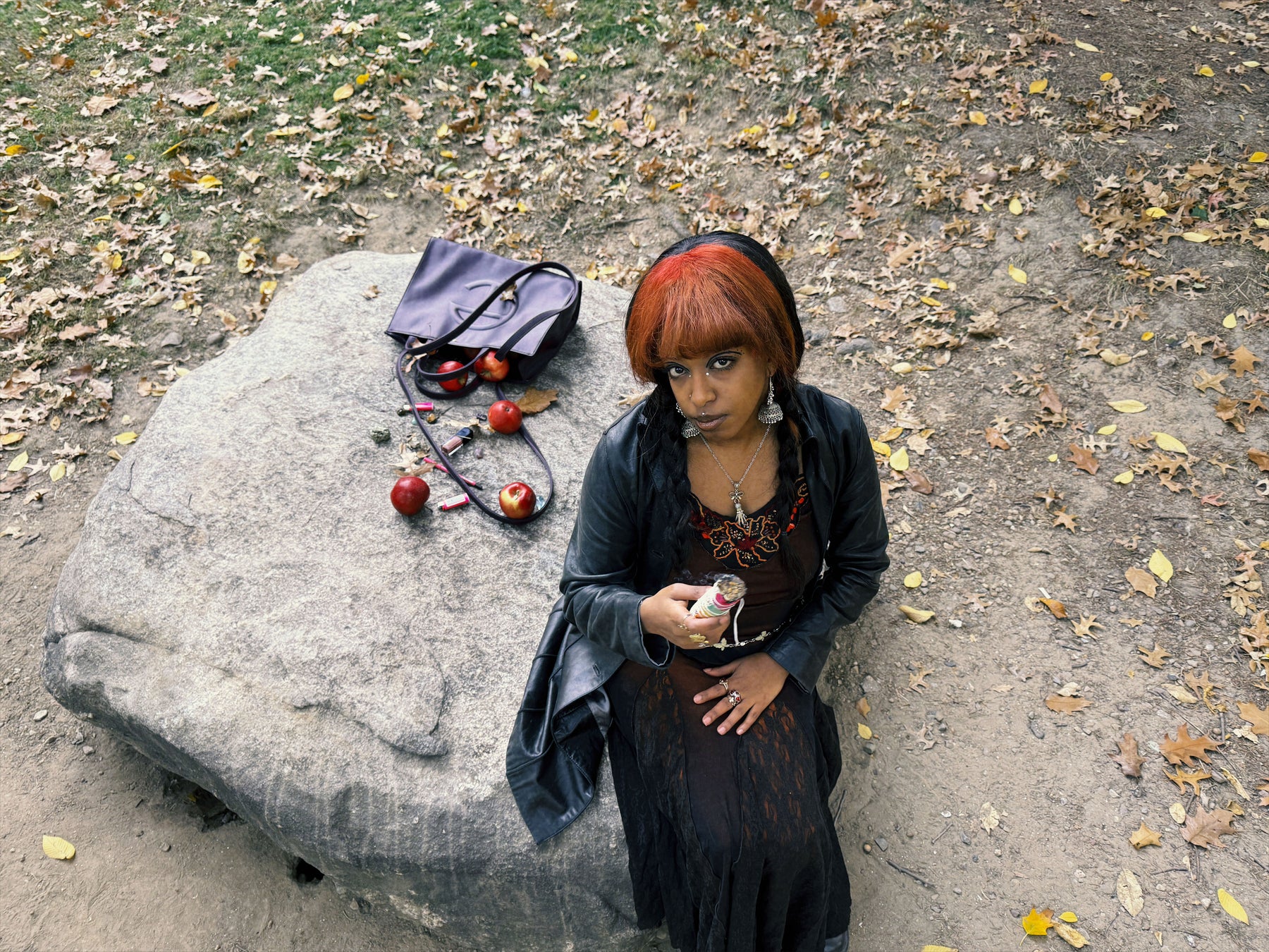 editorial shot of woman sitting on rock with purse full of apples