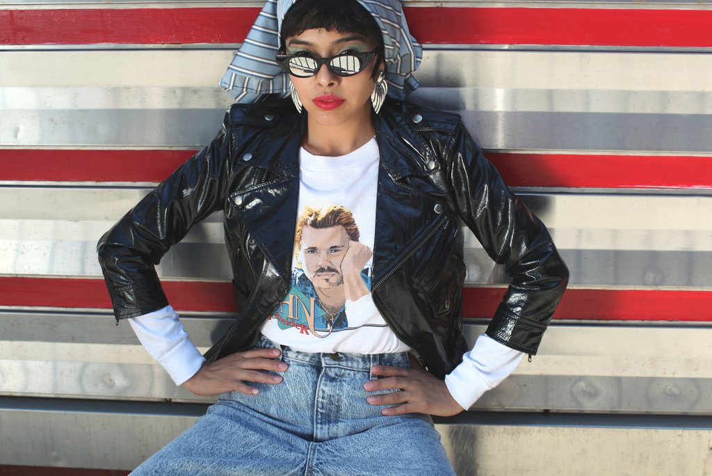 model in front of diner in leather jacket, jeans and reflective sunglasses.