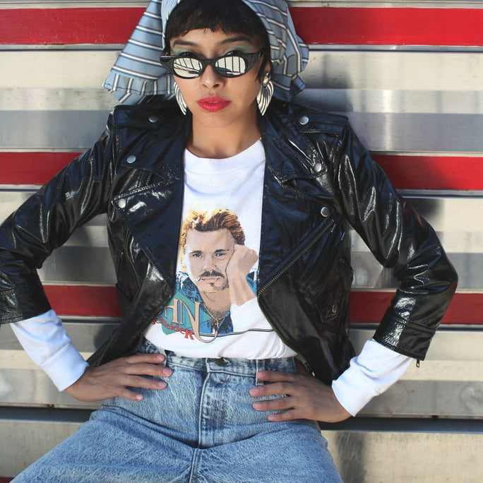 model in front of diner in leather jacket, jeans and reflective sunglasses.