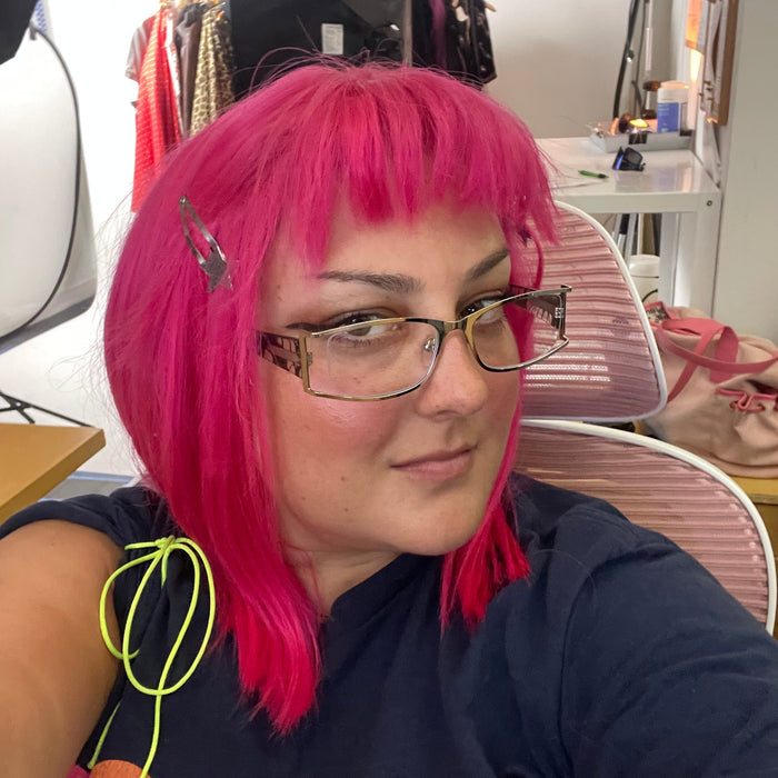 selfie of delcey sitting at desk behin product studio