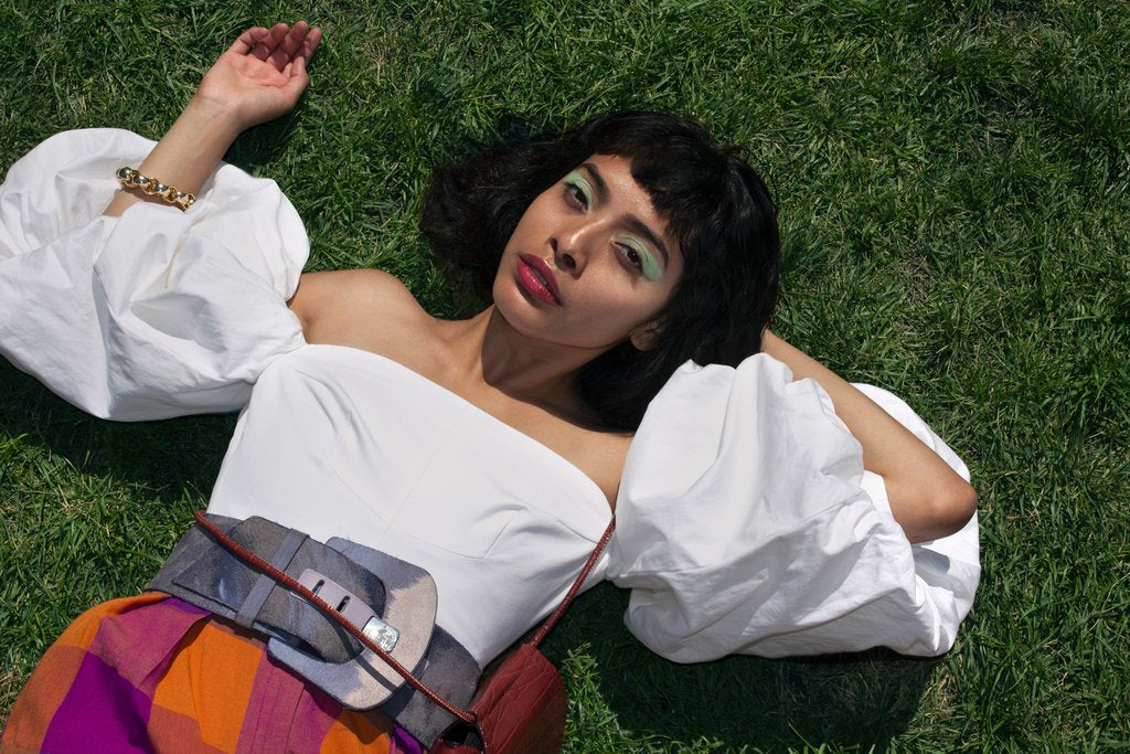 model laying down posing in the grass with puffy sleeves. 