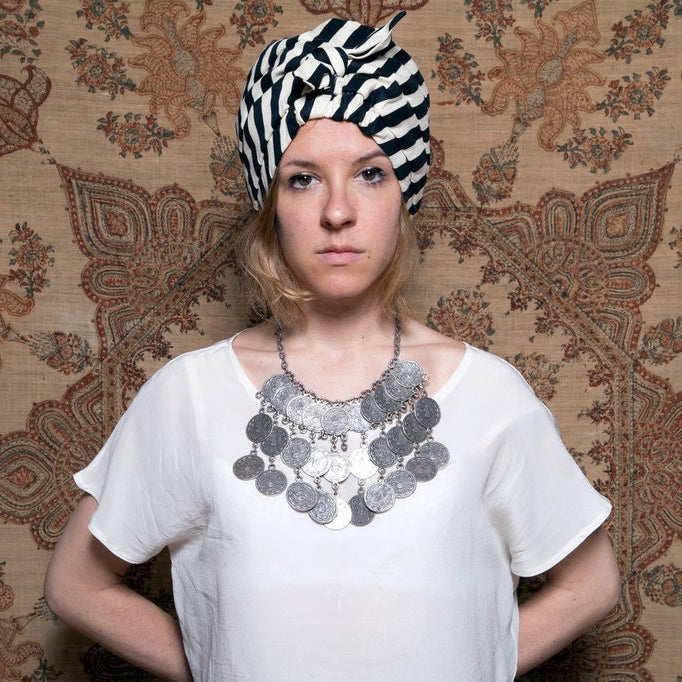 julia wearing a turban in front of a wall.