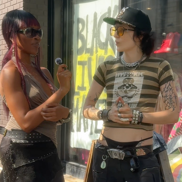 an image of odera and eliza in front of beacons closet store, doing an interview. theres a sign behind them that says "black lives matter"