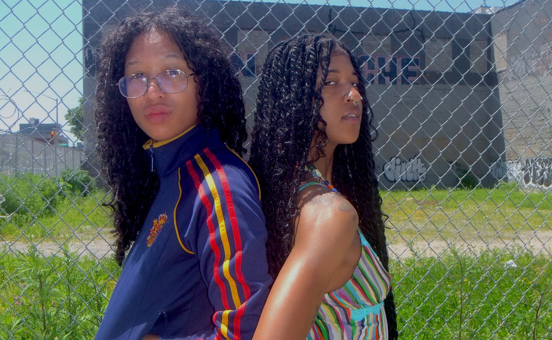 two people posing in front of chainlink fence