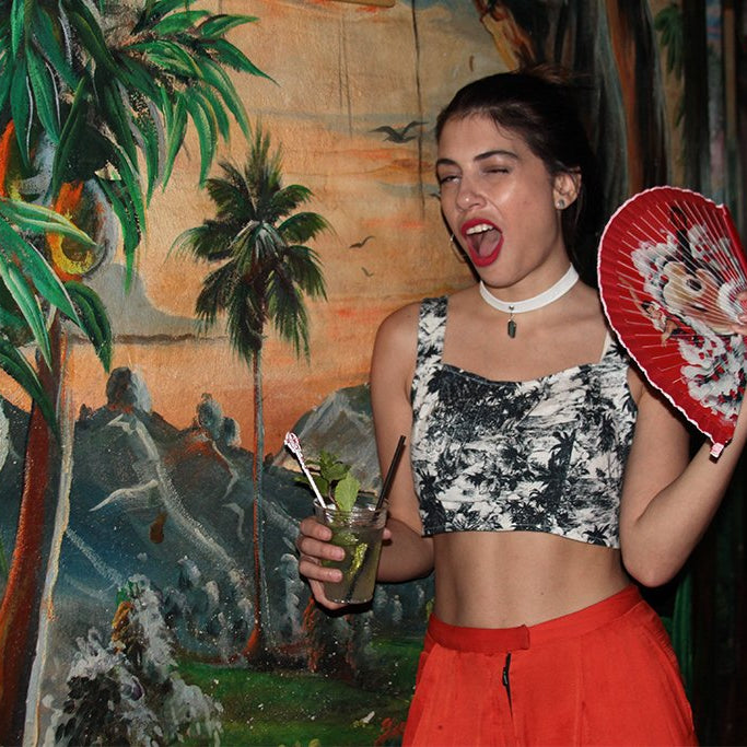 person posing holding fan and drink. 