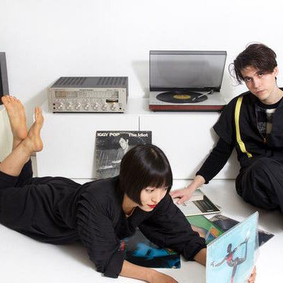 models laying around a record player and records. 