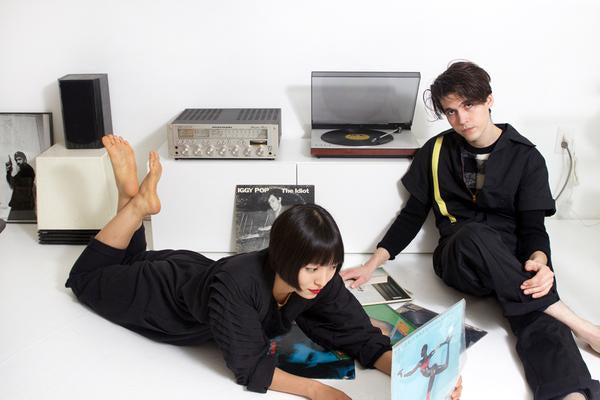 models laying around a record player and records. 