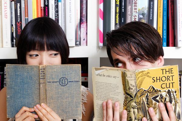 couple hiding behind books