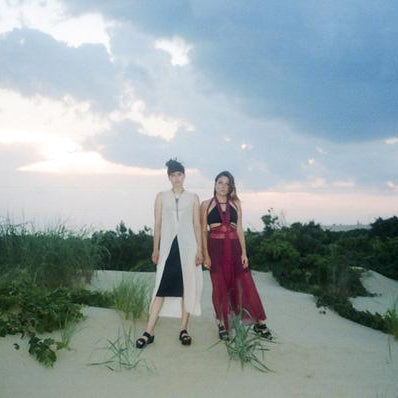 duo posing on a sand dune in front of the ocean.