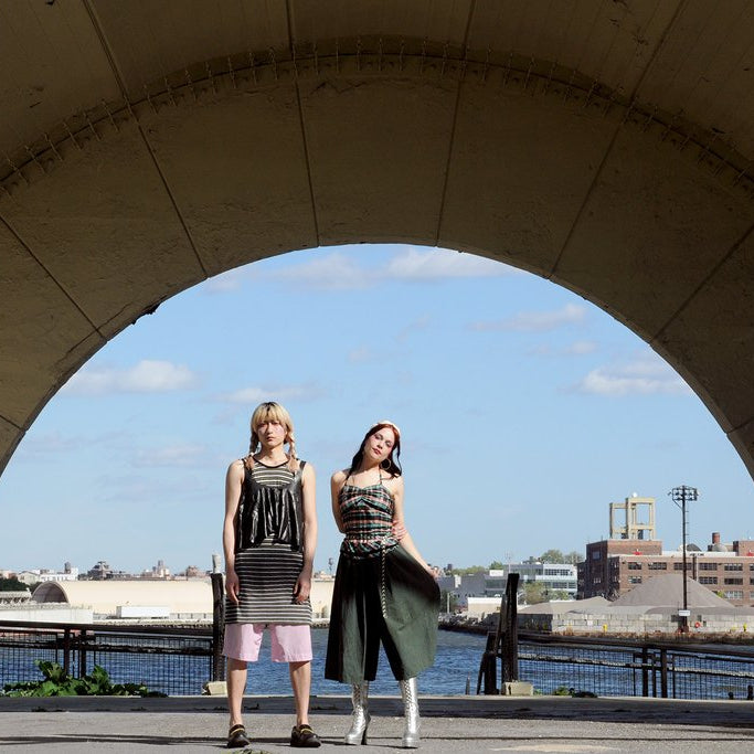 models posing in archway with water in the background. 