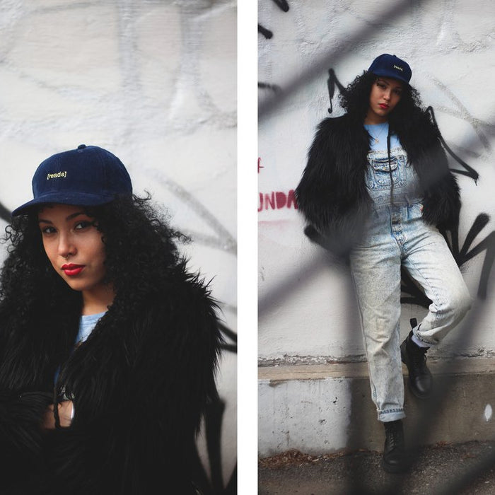 diptych of tangina stone in '{reads]' cap and fur coat and in denim overalls leaning against graffitied wall.