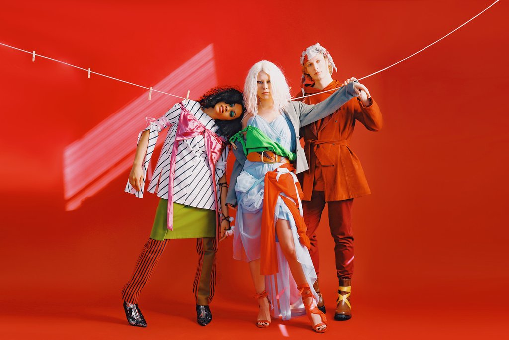 three models in layered conceptual looks with a clothes hanging line. 