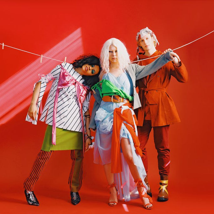 three models in layered conceptual looks with a clothes hanging line. 