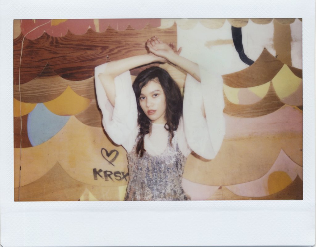 polaroid of model with arms above head. 