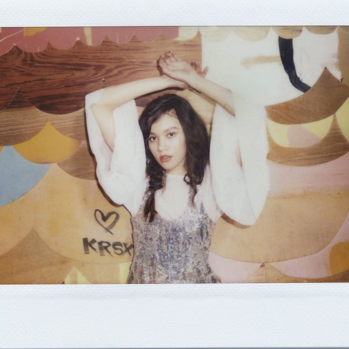 polaroid of model with arms above head. 