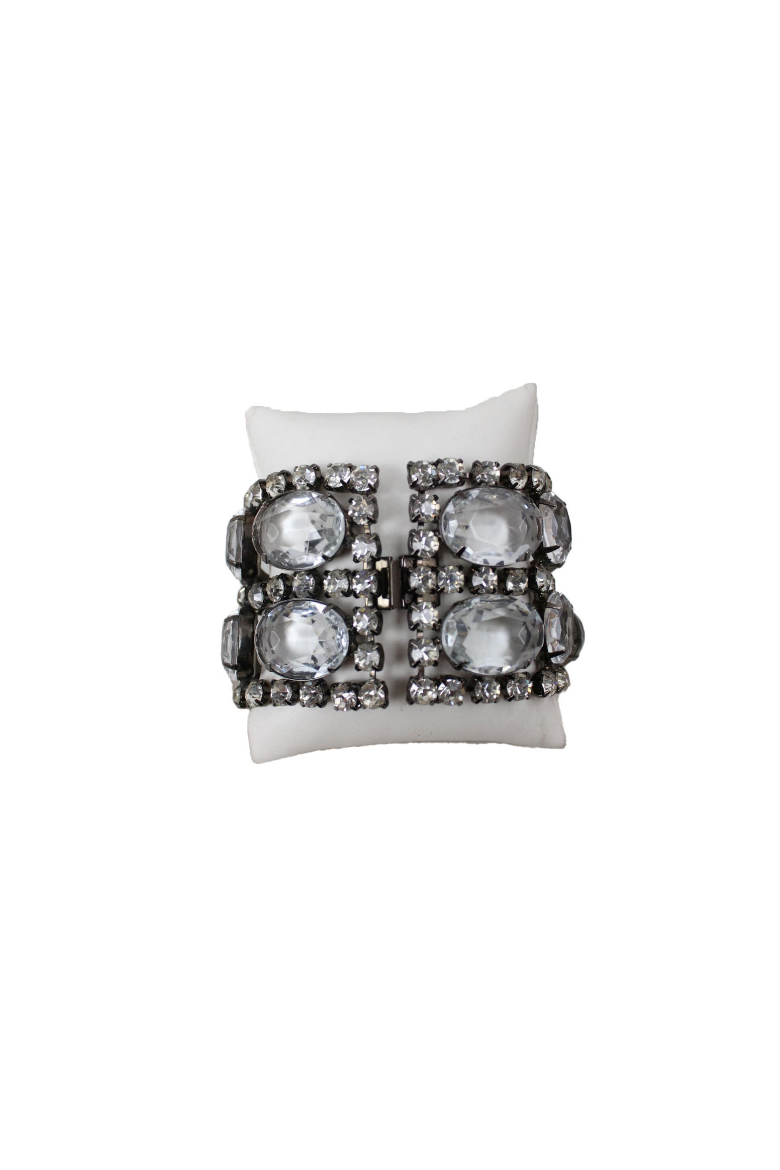 front of graziano silver tone bracelet. features rhinestones throughout, oval faux crystals detail, rectangular shape, and lock up closure. 