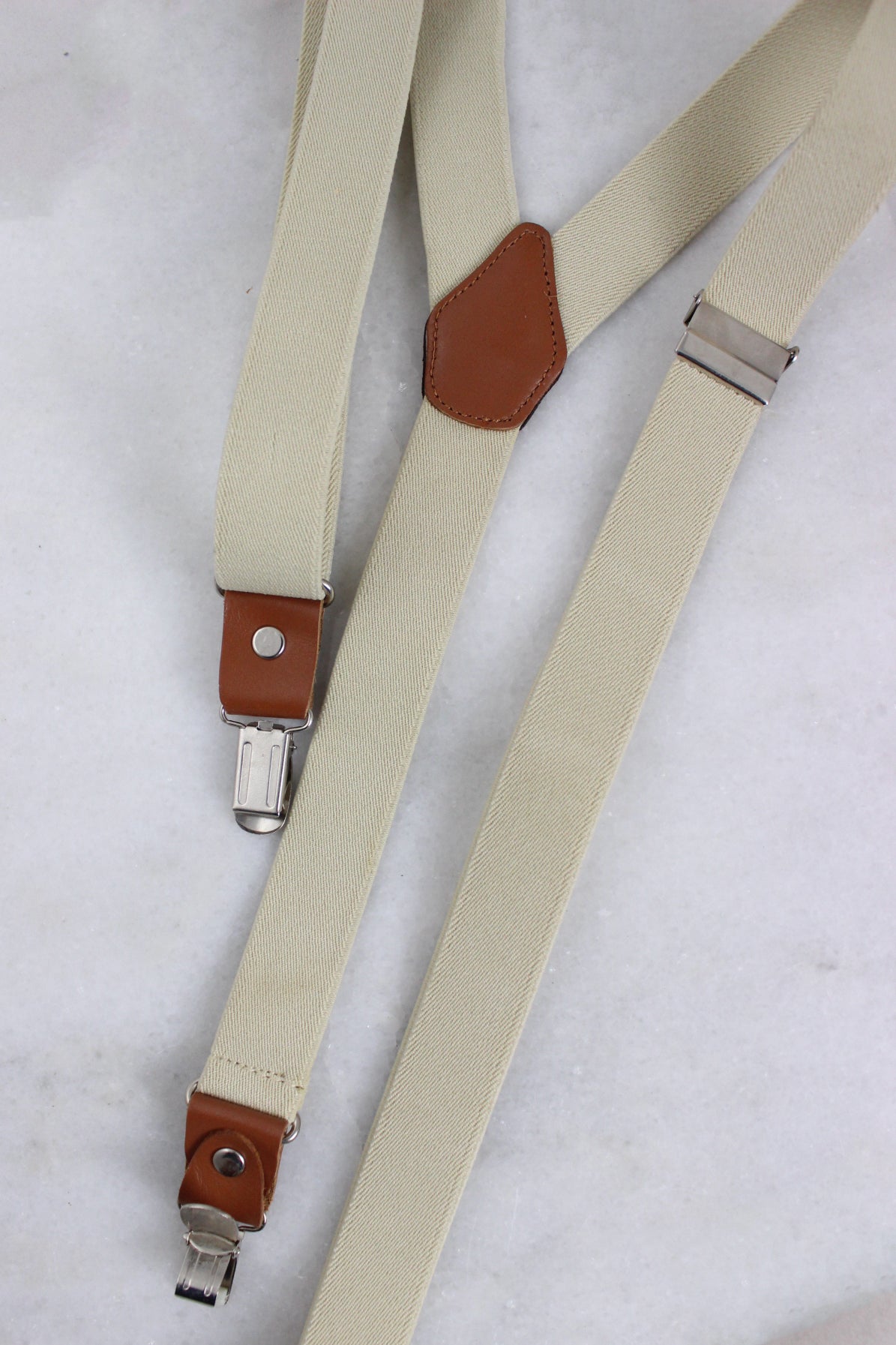 detail view with leather accents and metal clasps of suspnders.