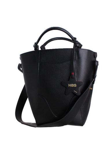 front of oleada x harvard business school black leather marina bucket bag. chic bucket bag design that can fit a 14" laptop plus more. adjustable long shoulder strap and double top handles. two sleek side outer pockets. red suede interior. branded red/black star bag charm. 