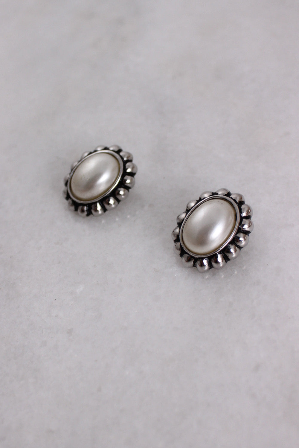 ¾ aerial view of earrings highlighting center opalescent bead and scalloped edges