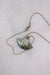top view of necklace laid flat showcasing lobster claw style closure and opalescent shell-shaped pendant. 