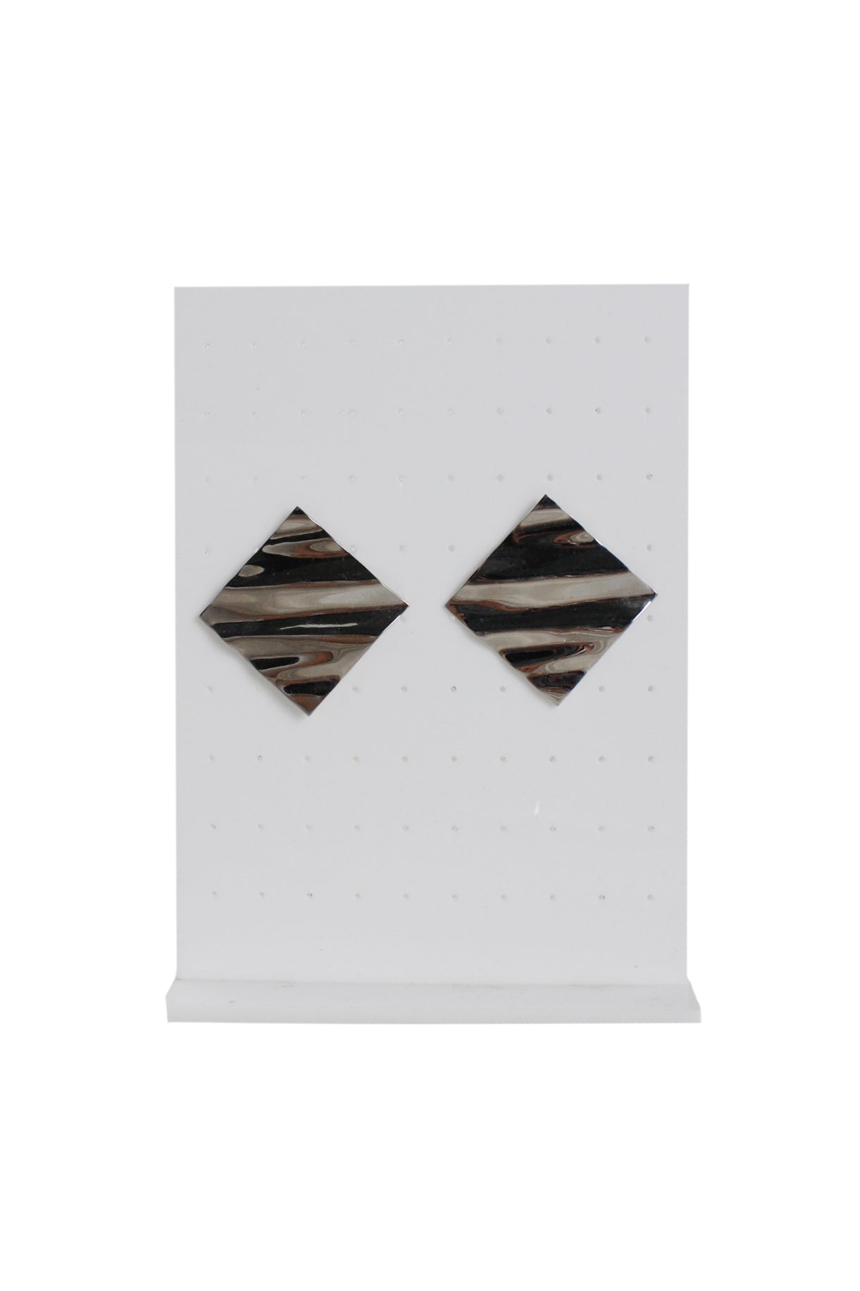 front of silver metallic square earrings against earrings stand