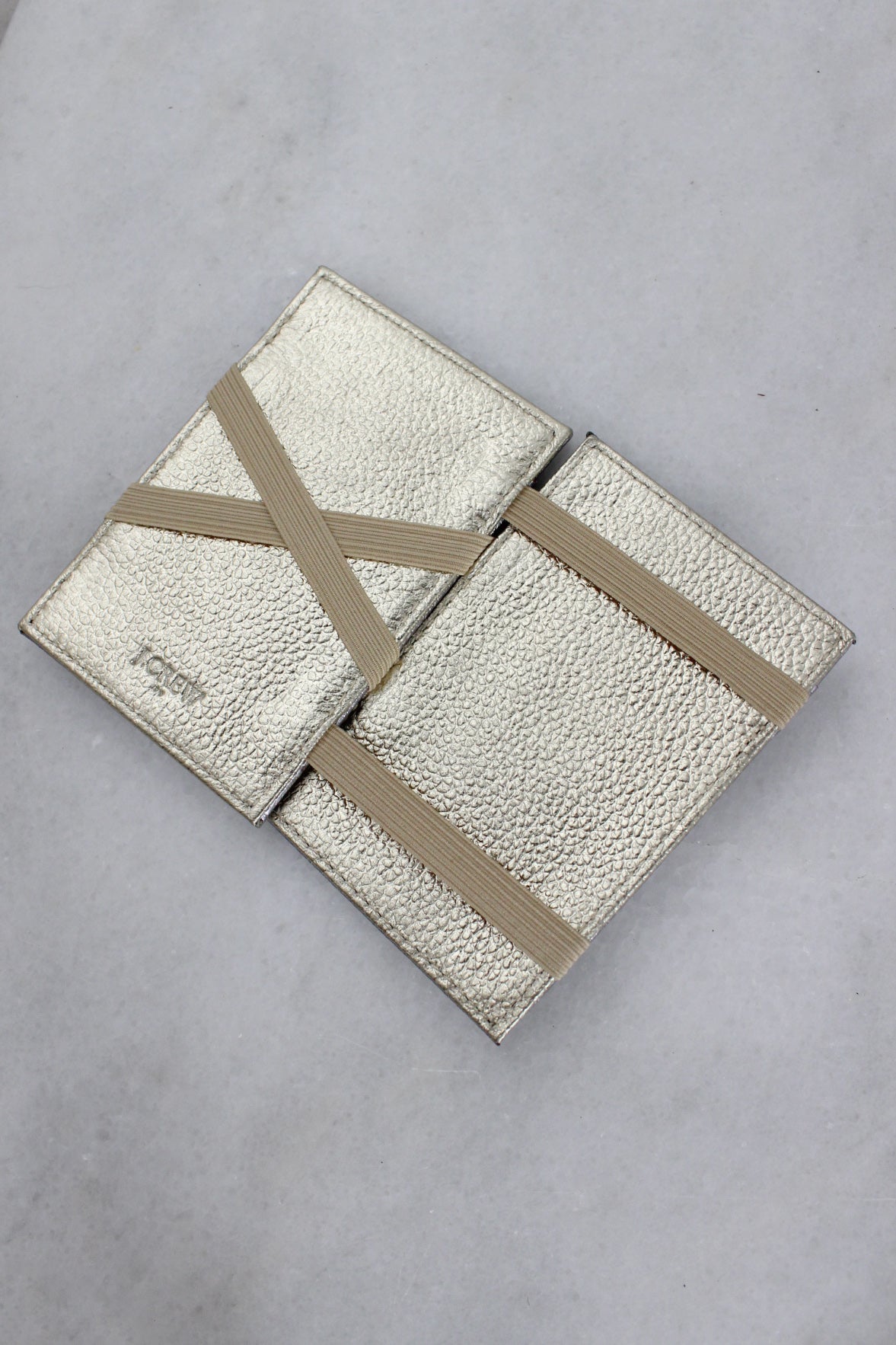 opened interior angle j.crew faux leather dual card holder featuring gold interior with tan elastic banding & 'j.crew' embossed text at lower corner.