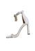 angled side view of white leather heeled sandals with fringe strap
