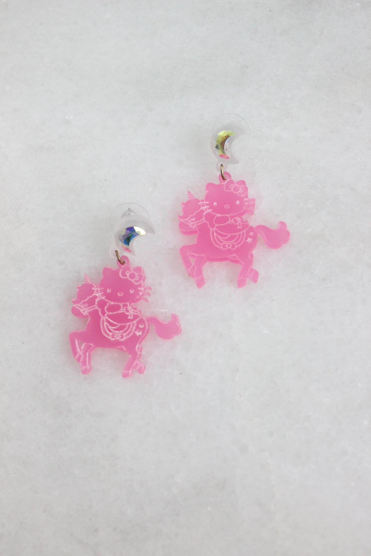 top view of pink earrings laid flat showcasing the carved character detail.
