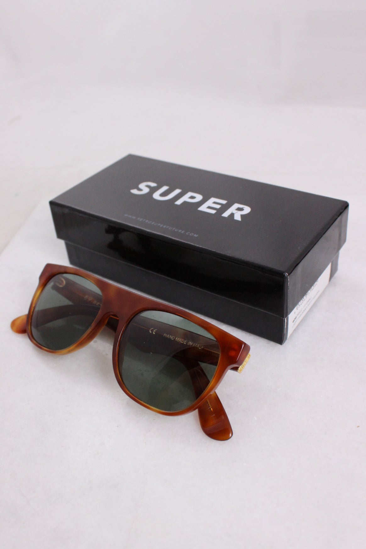 ¾ angled image of brown sunglasses staged against branded box reading ‘super’ in oversized font.