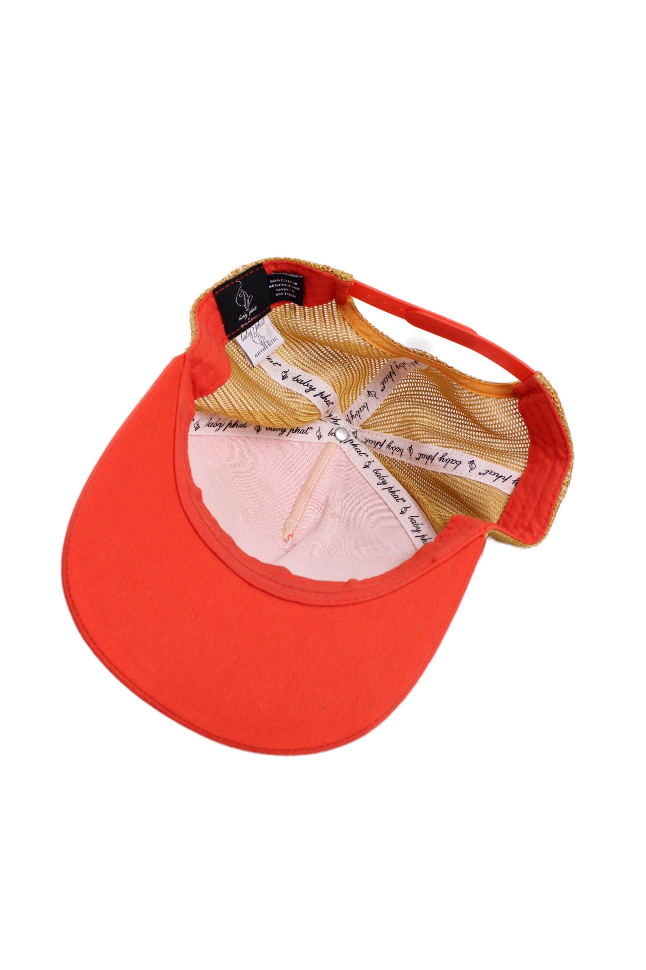 angled image of the orange trucker hat laid flat upside down showcasing the cap’s interior and branded trimming reading “baby phat”