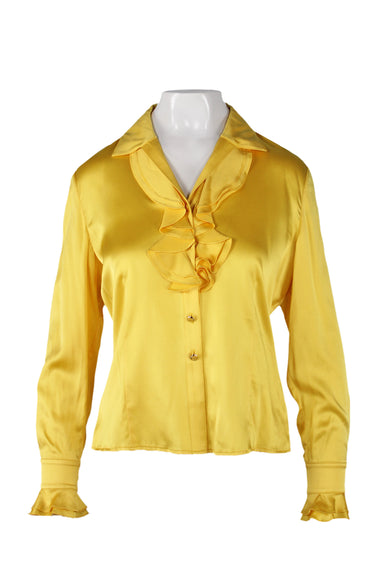 front angle of st. john golden yellow silk blouse on fem mannequin. features shiny soft silk fabric throughout, long sleeves with ruffled cuffs, v-neckline with pointed collar and double ruffle, button closure up center, and buttoned cuffs. 