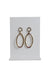 gold toned metallic hoop earrings with a golden tube framed leather loop drop staged on an earring stand
