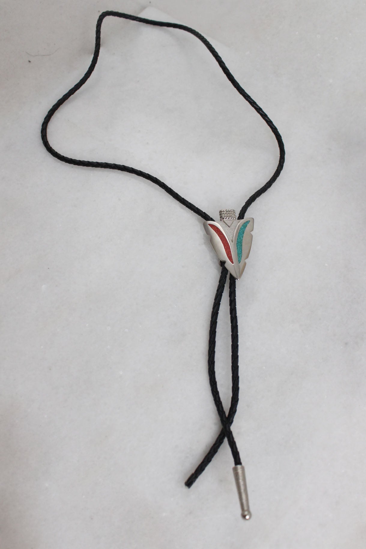 top view of bolo tie laid flat showcasing the missing metallic tip