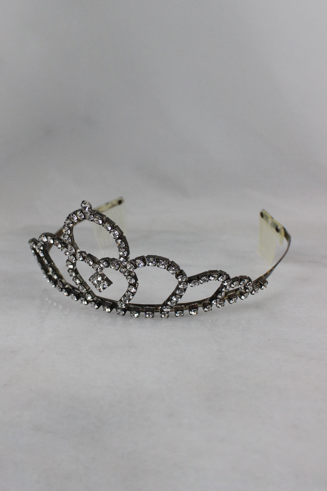 detail view of unlabeled tiara with round cut gems, metal frame and plastic hair combed teeth.