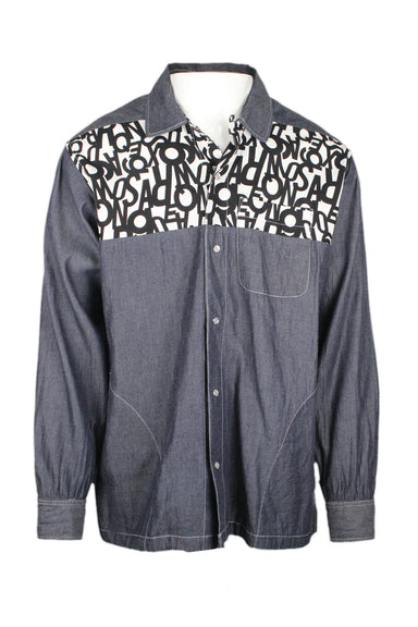 front view of aie new york indigo/black/white long sleeve snap button up denim shirt. features letter pattern panel at chest/upper/back, left breast pocket, side hand pockets, drawstring at hem, and snaps at cuffs.