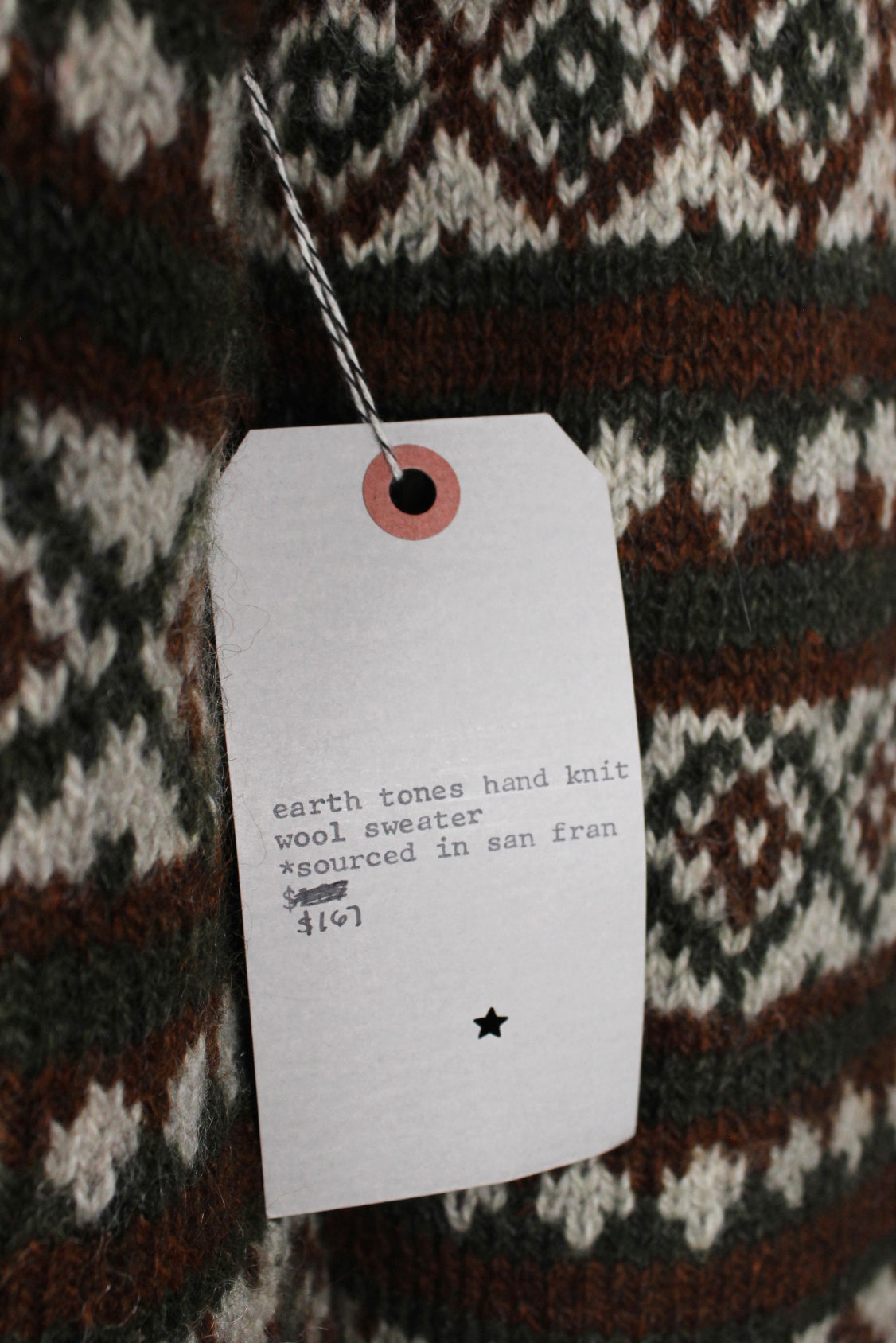 detail view of 'earth tones hand knit wool sweater *souced in san fran $167' price tag on sweater.