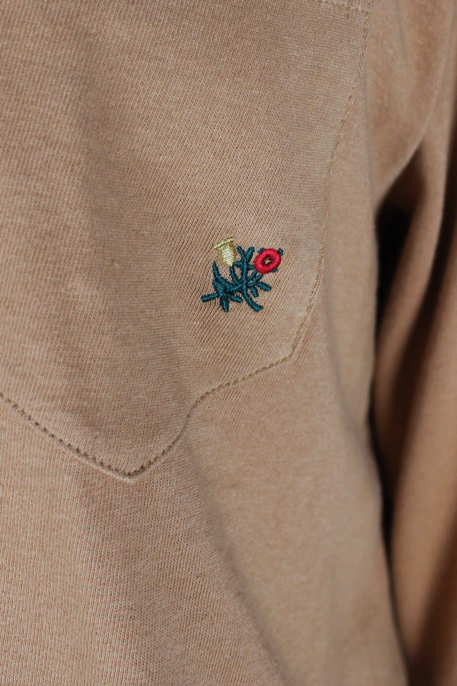 detail view of embroidery at left breast pocket of shirt.