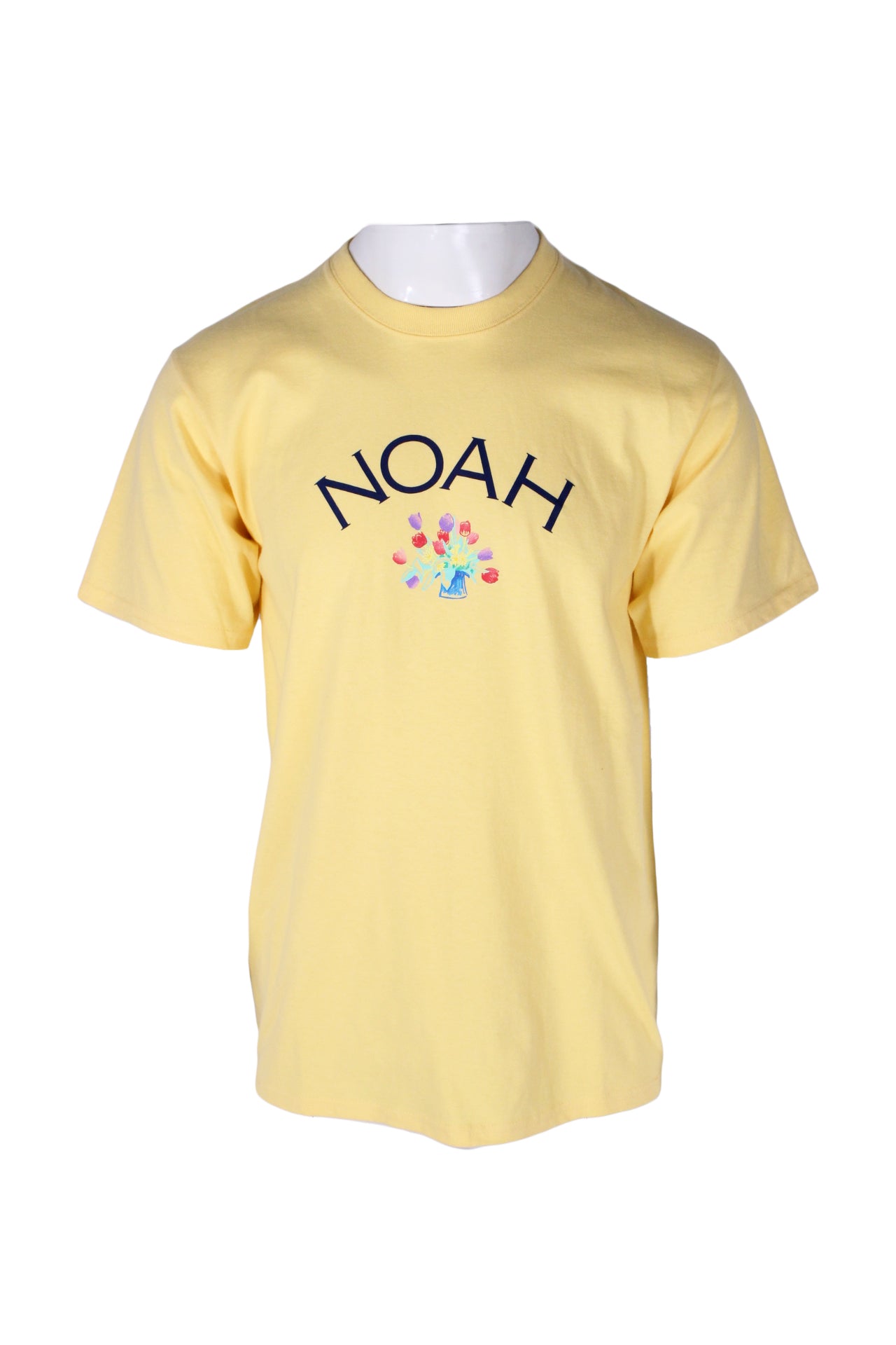 front angle noah x tom wesselmann daffodil yellow short sleeve 'logo lock up tee' on masculine mannequin torso featuring multicolor flower graphic & midnight 'noah' text at chest and rib knit crew collar.