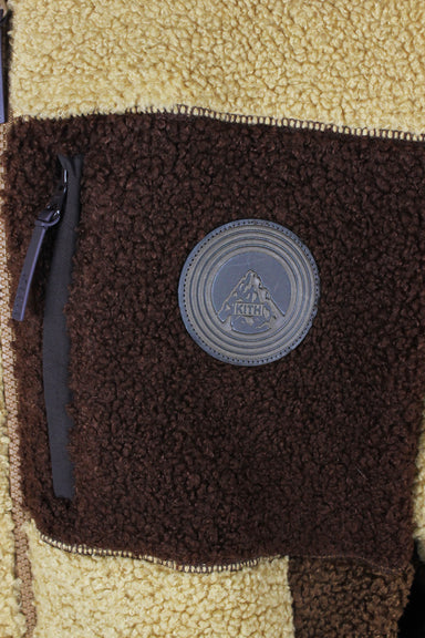 detail view of 'kith' logo tag at left breast zip pocket of jacket.
