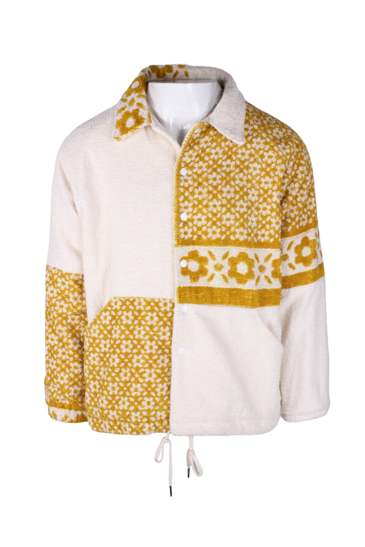 front angle of isabel hall yellow and cream terry cloth jacket on masc mannequin torso. features drawstring hem, snap button closure, long sleeves, angled slit hand warmer pockets, and floral patterned color block pattern throughout. lined. 