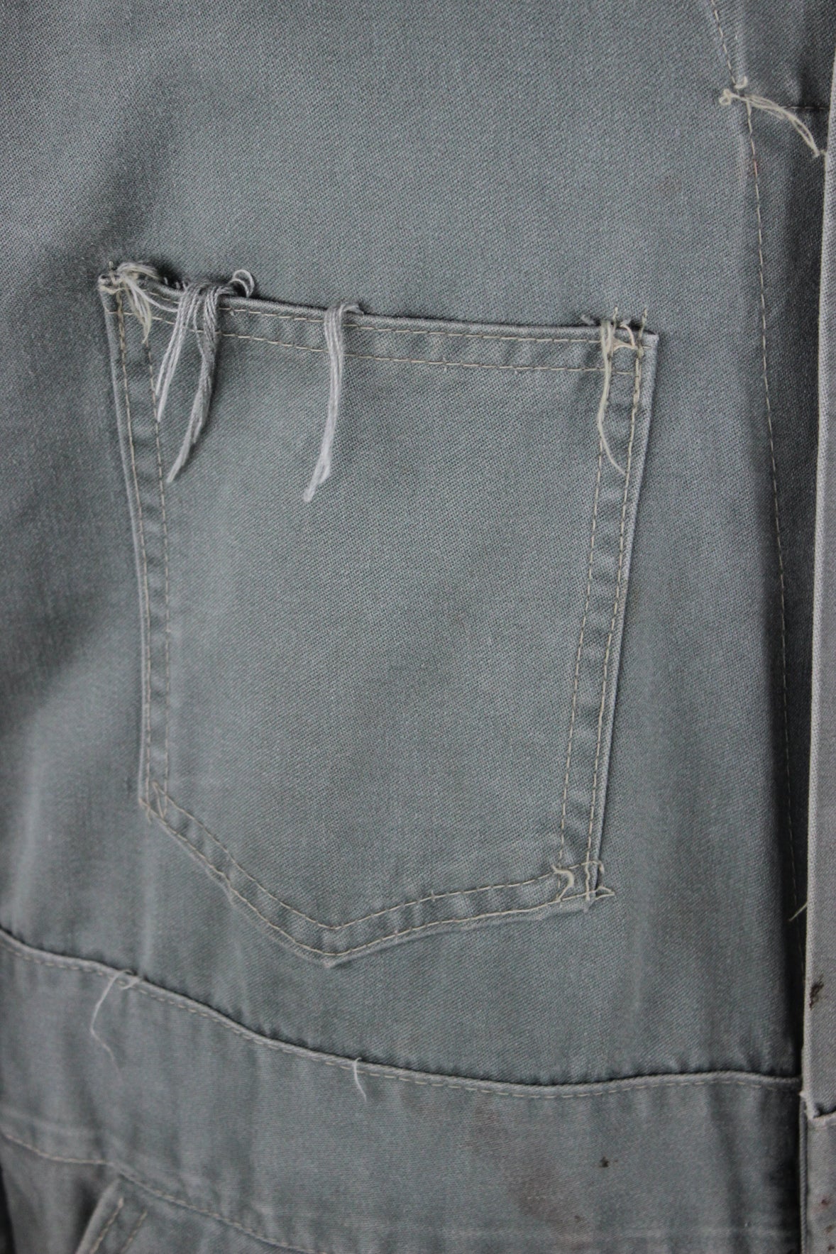 detail view of fraying at left breast pocket of coveralls.
