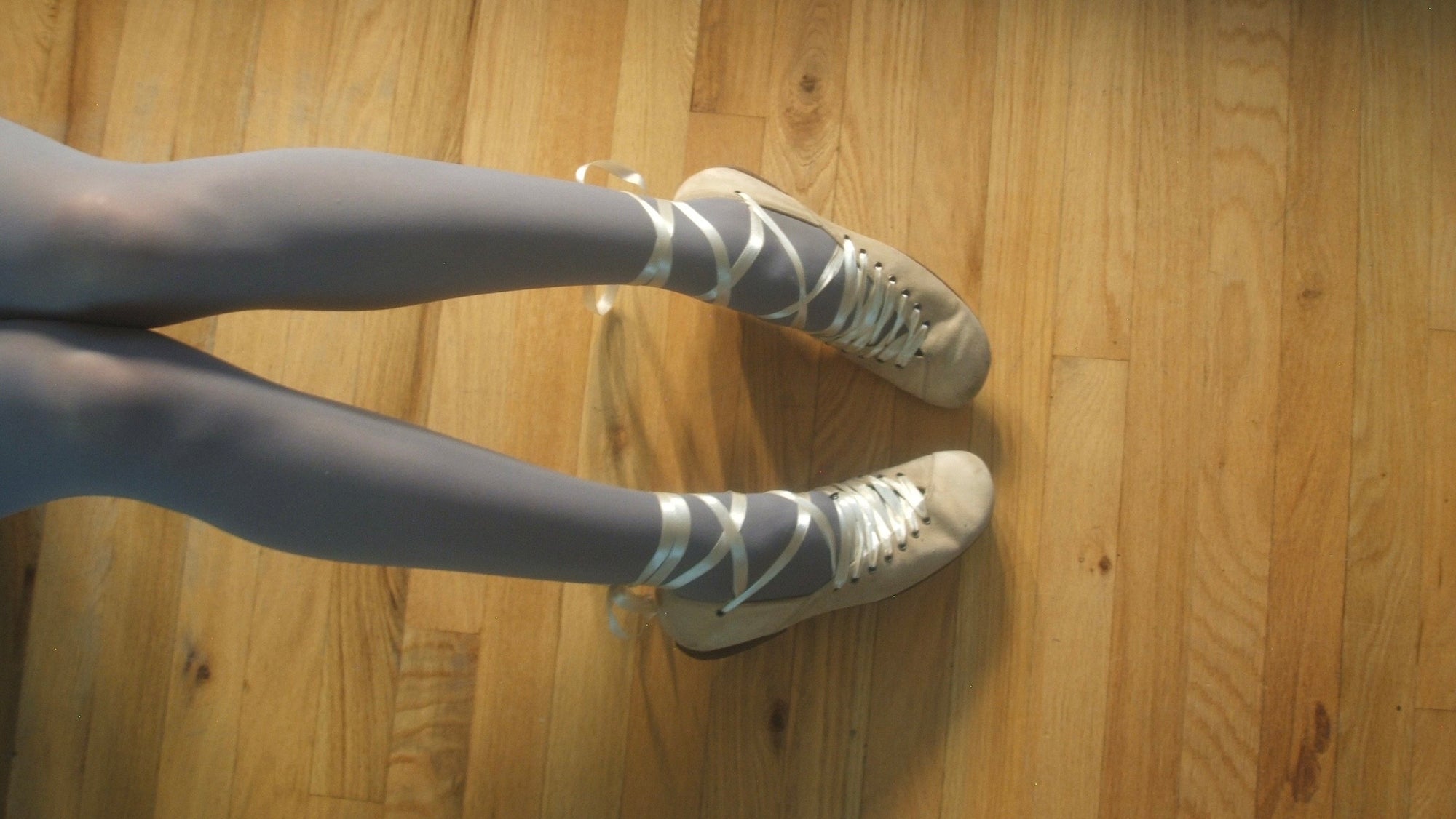 person wearing blue tights and ballet sneakers on wooden floor