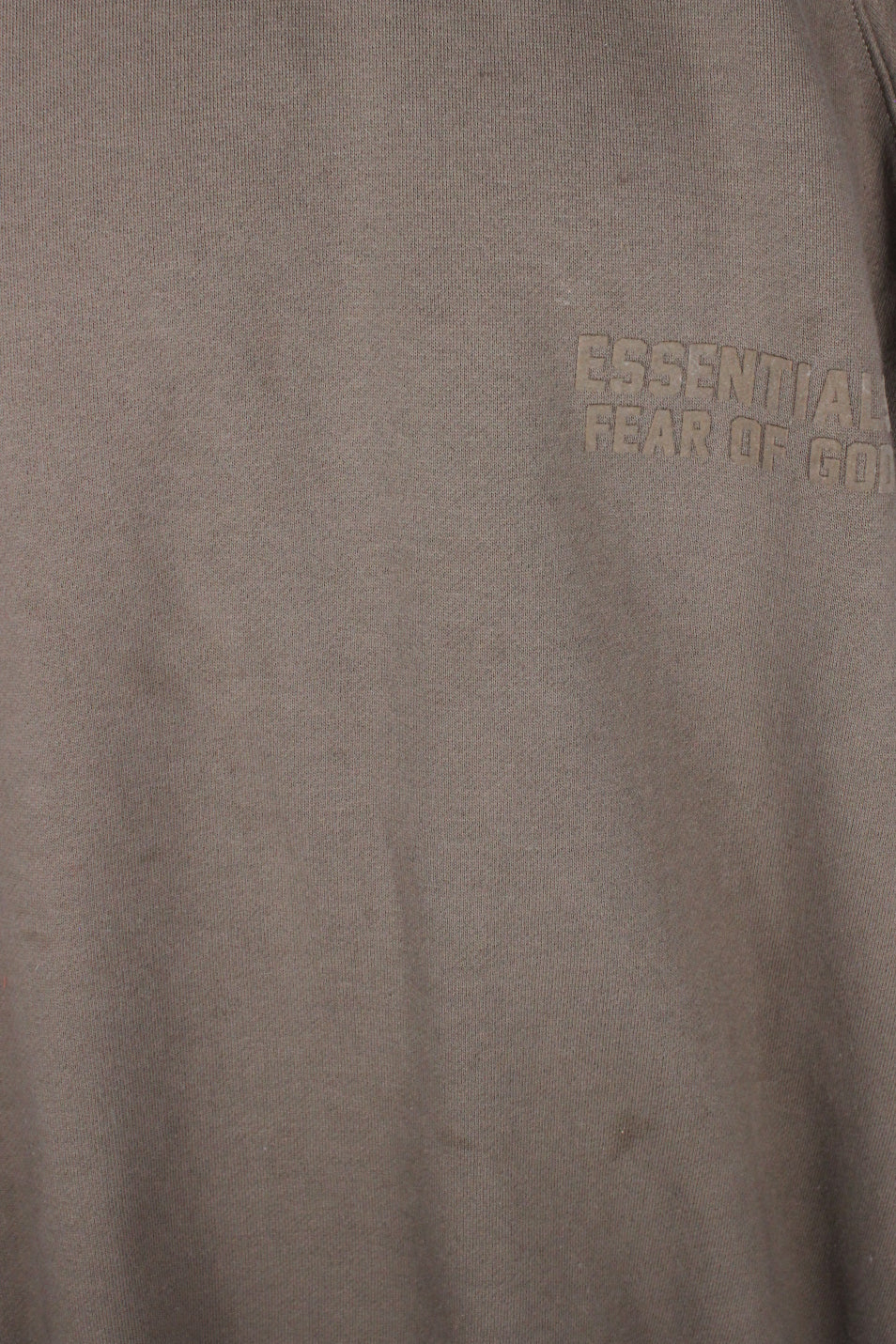 detail view of stains at front below 'essentials fear of god' felt letters at left breast of sweatshirt.