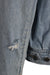 detail view of hole at left sleeves elbow of jacket.