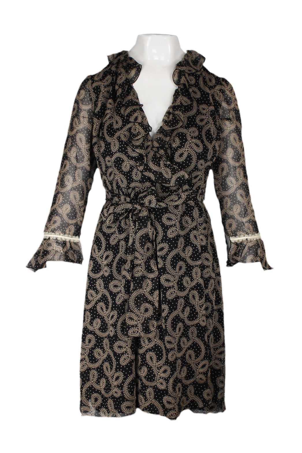 front of anna sui black/beige pailsey print ruffle wrap dress. v neckline with ruffled collar. sheer 3/4 length sleeves with ruffle sleeve cuff and lace trim. cross-over snap button and hook-and-eye closure at waist with tie belt. this garment is a production sample, and is missing the interior size and care tags.