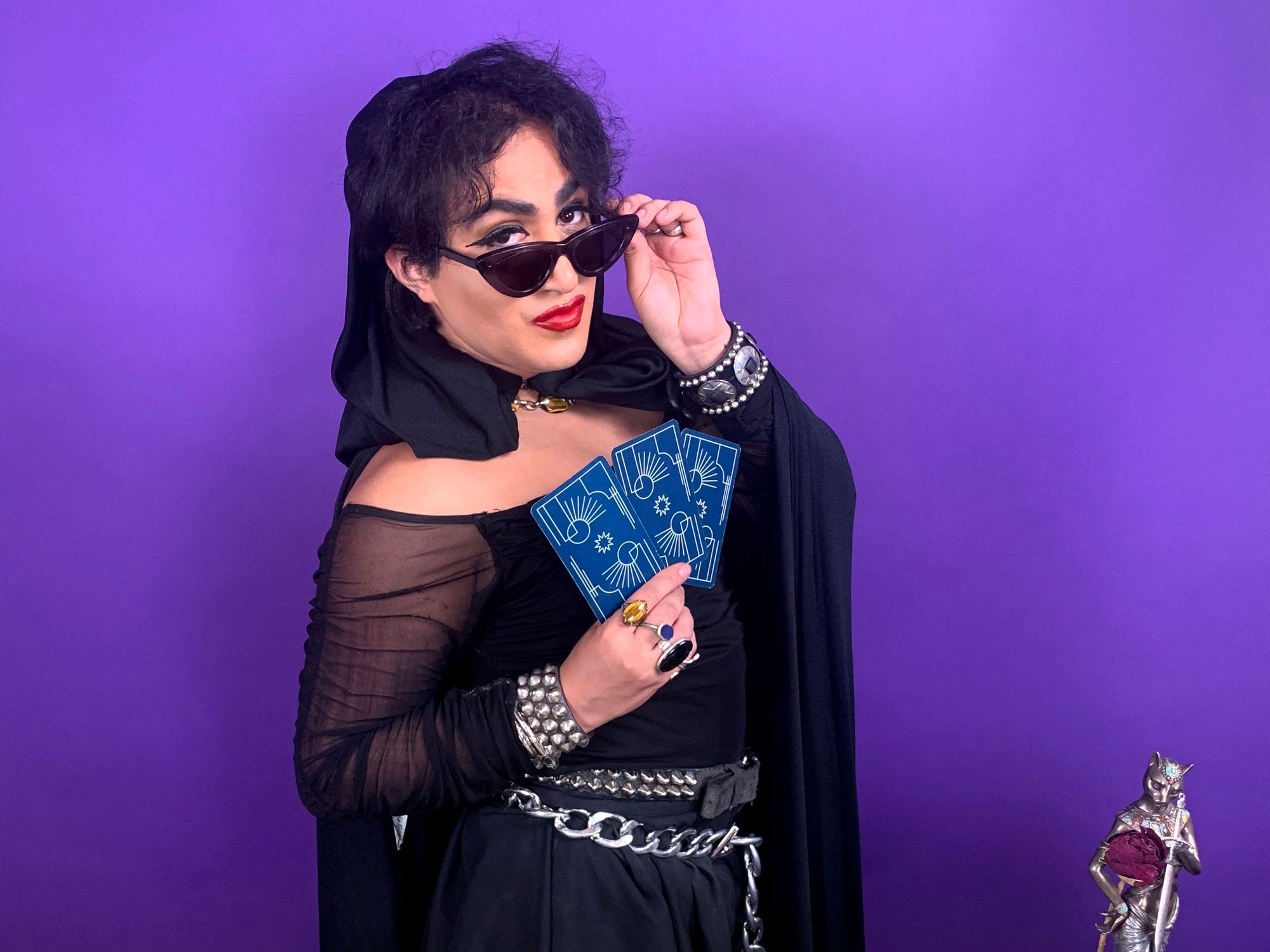 person posing with tarot cards infront of purple backdrop