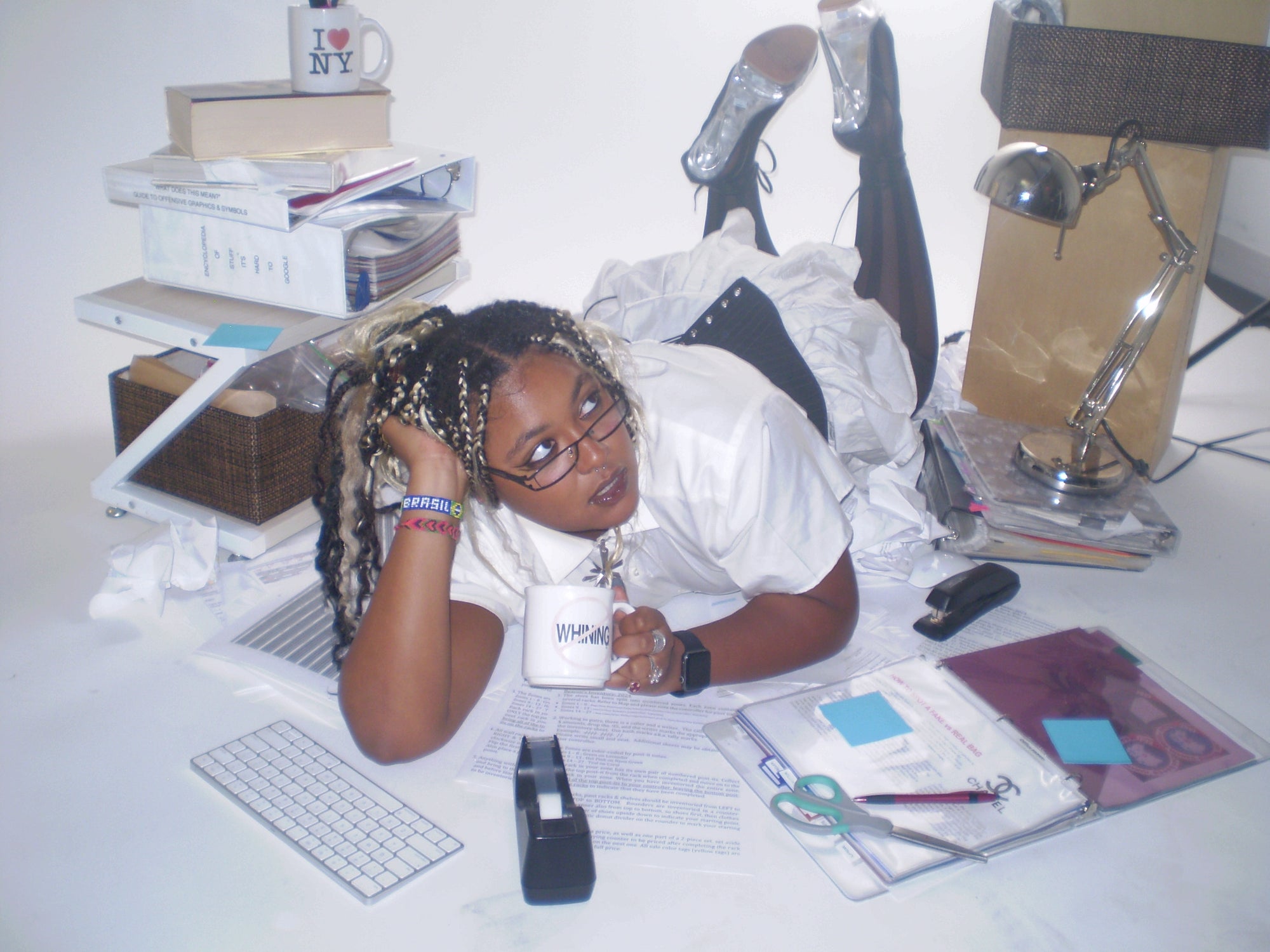 editorial of Person lying on a ground with books, a computer, and office supplies around them.