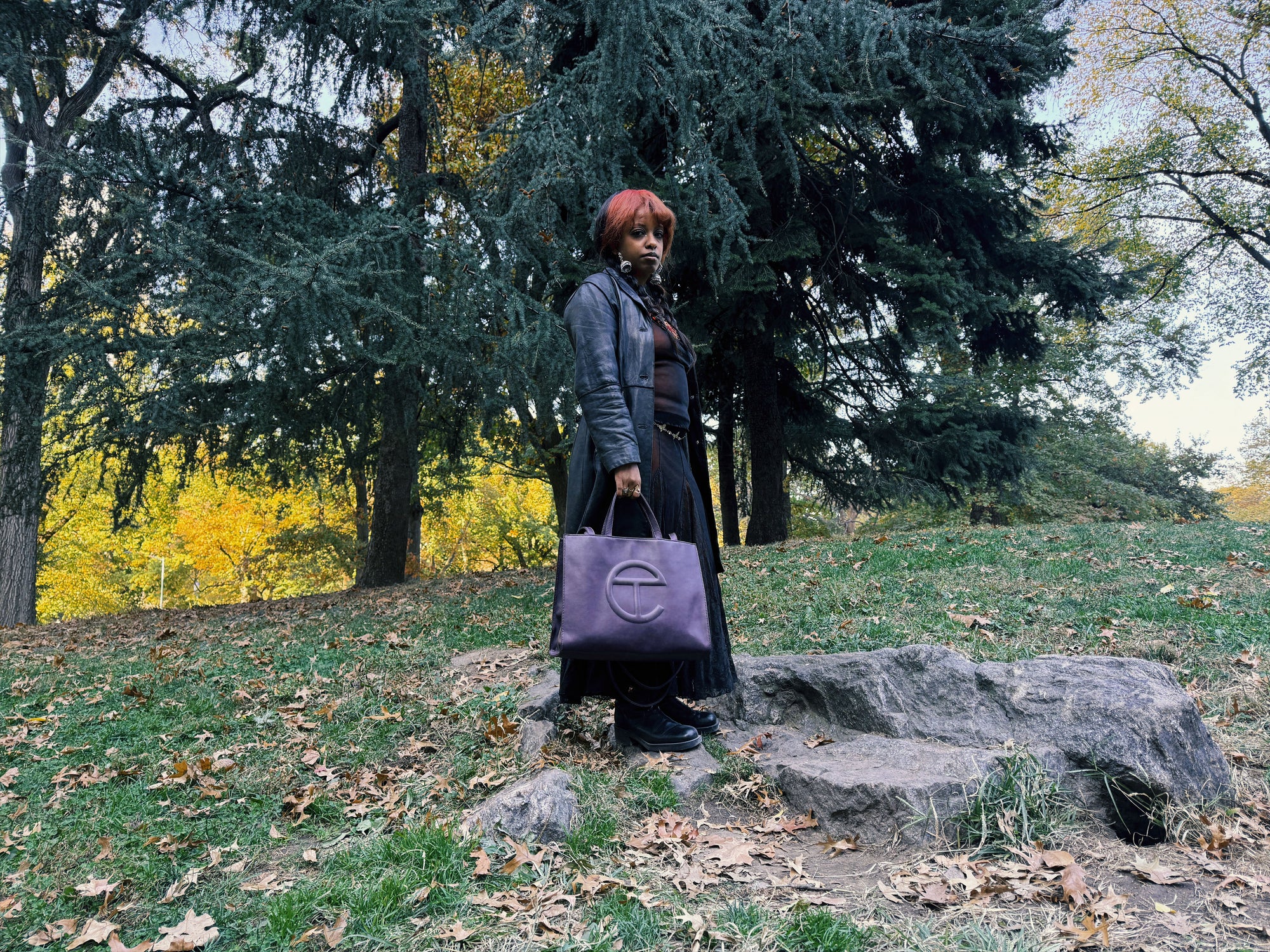 editorial shot of woman posing on hill in park with telfar bag