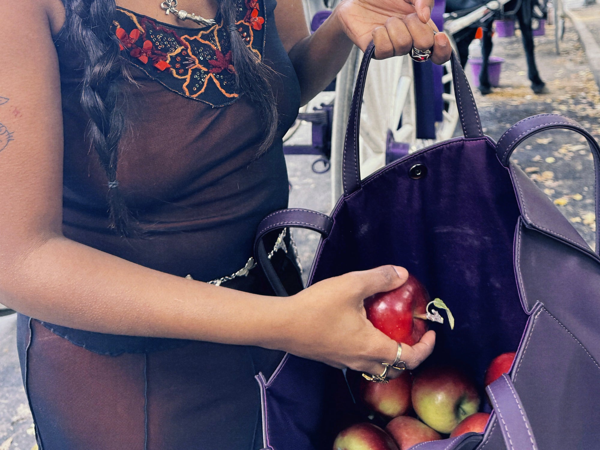 artistic photo of woman placing apples in large telfar tote in central aprk